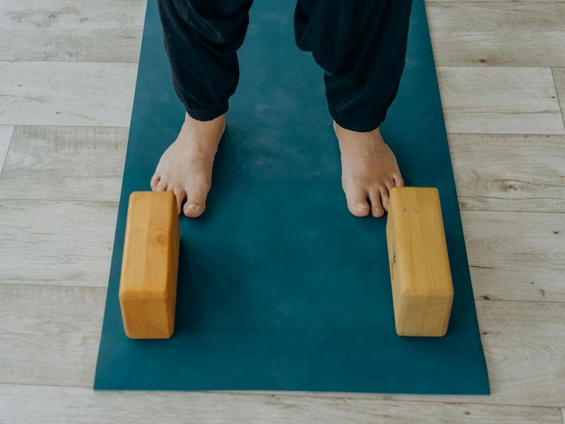 Sequence of yoga blocks and water bottle on a dark wooden floor